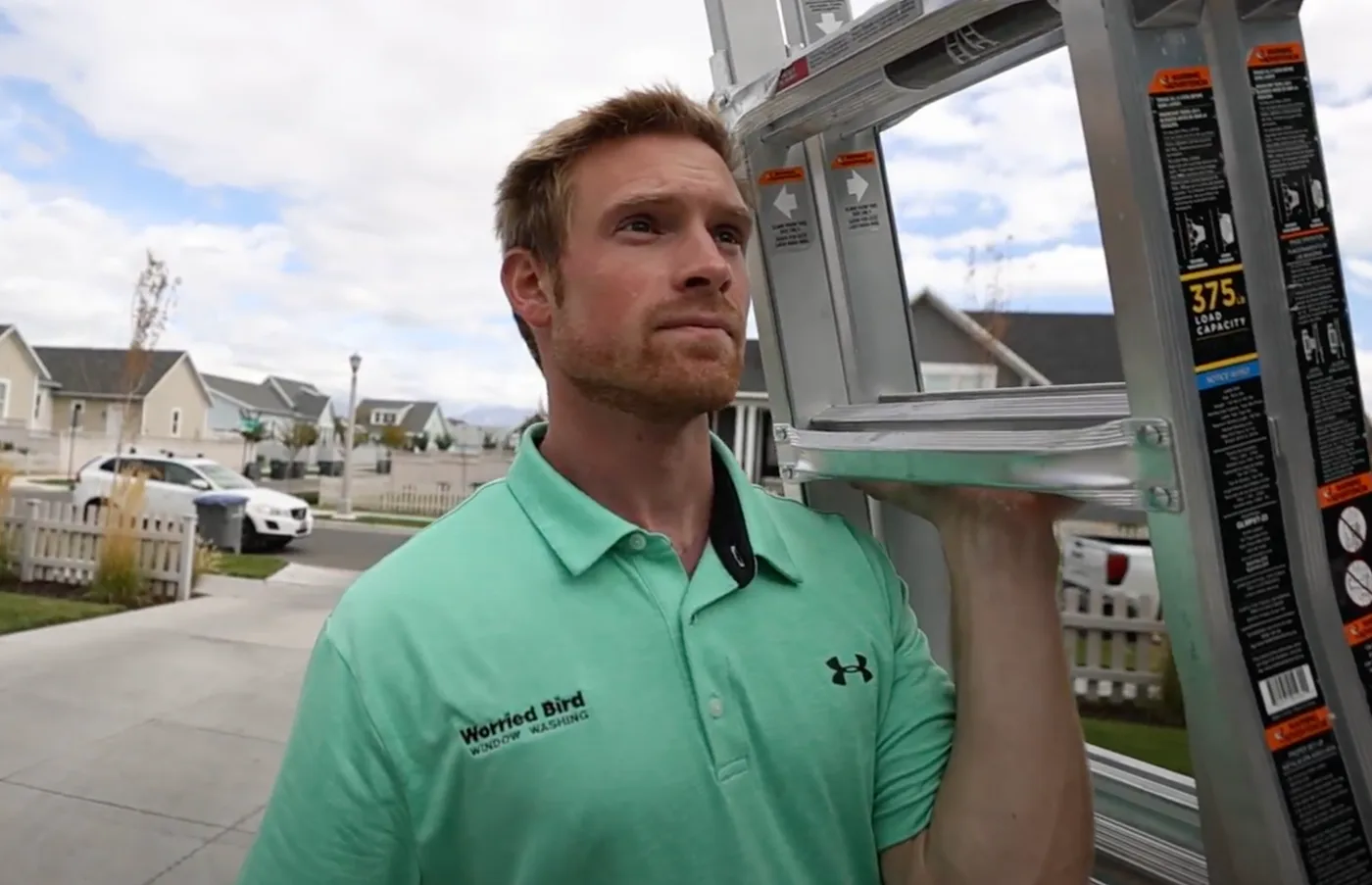 A Worried Bird team member carrying a ladder to a home for a window cleaning visit.